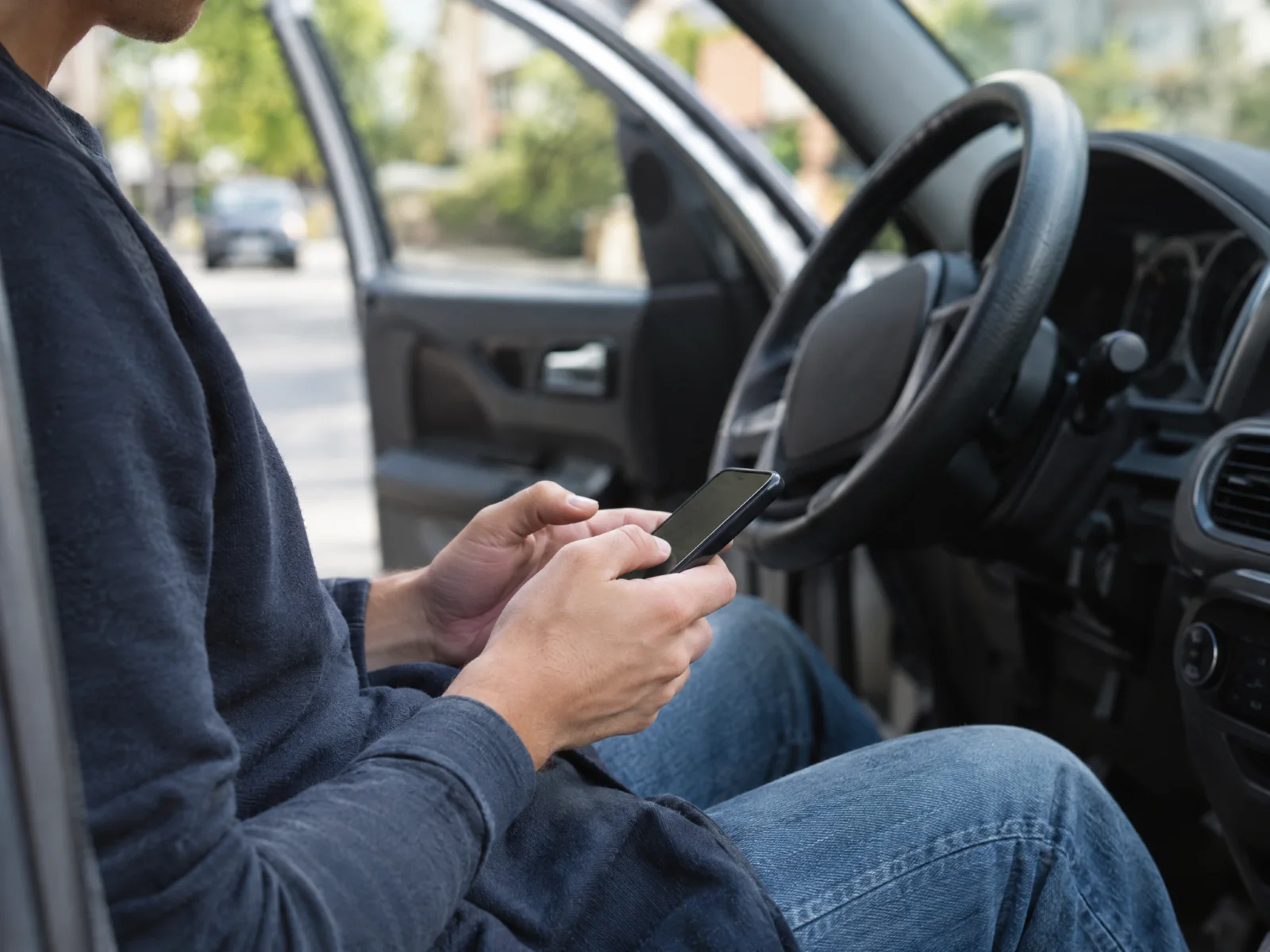 A car owner using a phone in a parked car