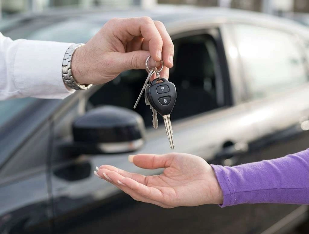 Car keys handed from a private seller to a buyer
