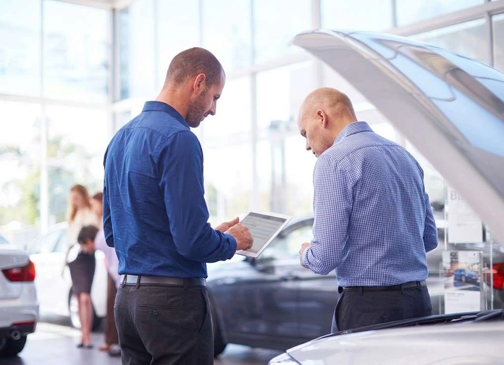 Two buyers reviewing a vehicle on a tablet in a showroom