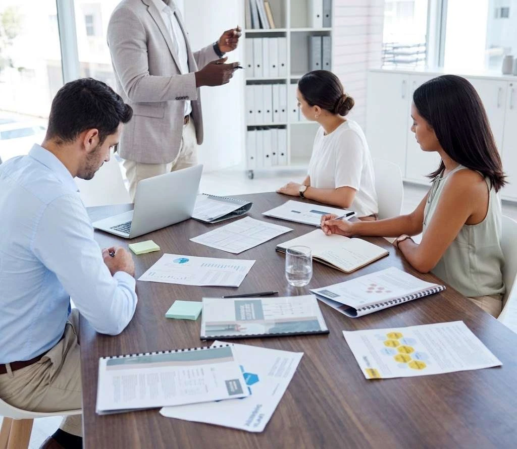 A trainer coaching a dealership team with playbooks
