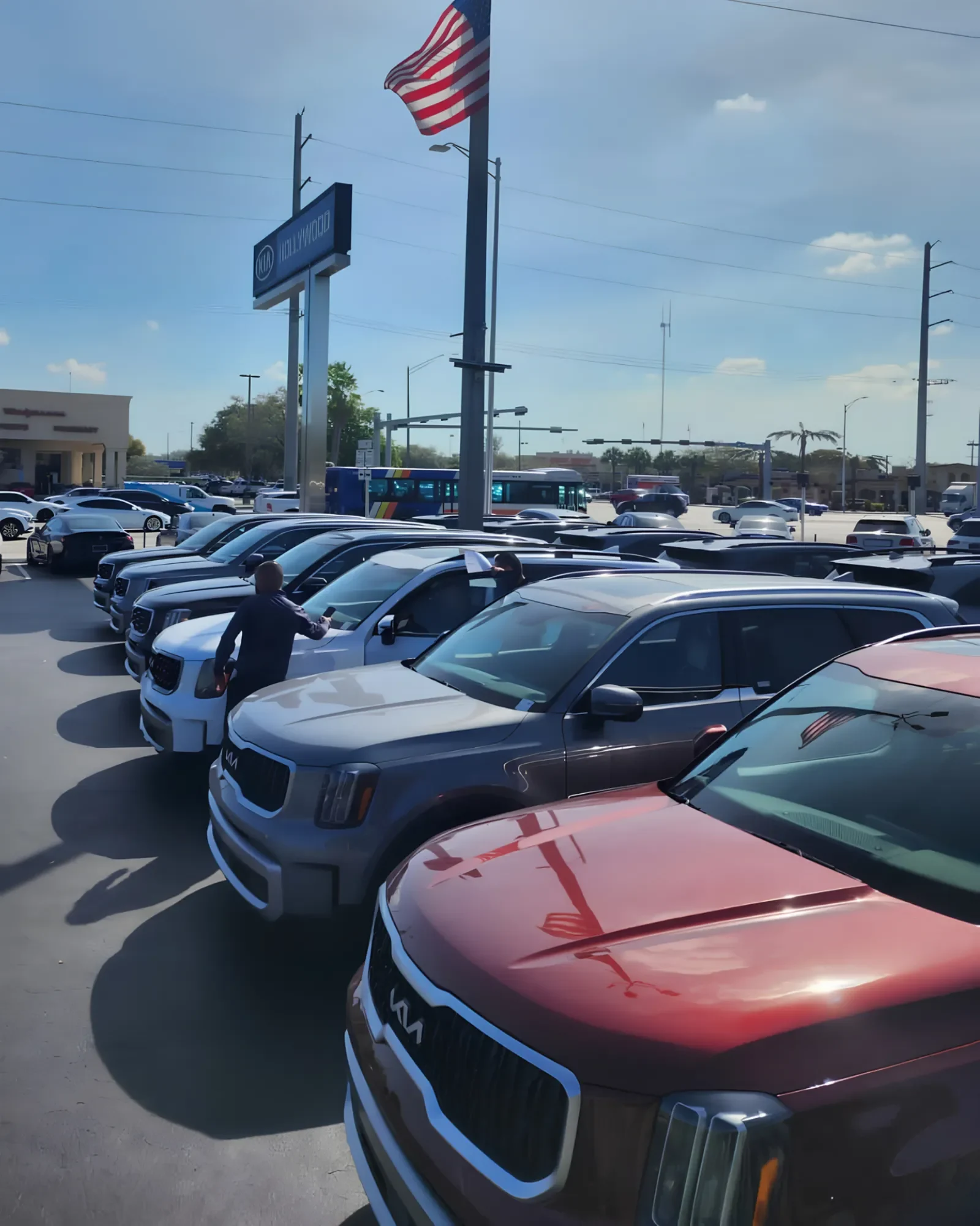 Rows of SUVs on a dealership lot with a buyer checking a vehicle